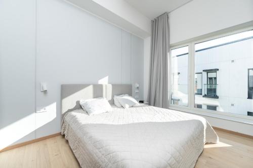 biała sypialnia z łóżkiem i dużym oknem w obiekcie Brand new 2bdroom Free Parking Apartment w Tallinnie