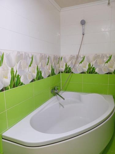 a bathroom with a toilet with green and white flowers on the wall at Villa Zgarda1 in Mykulychyn