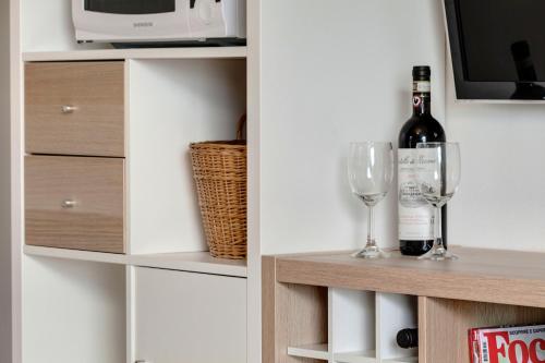una botella de vino y una copa de vino en un estante en A casa di Anna, en San Miniato