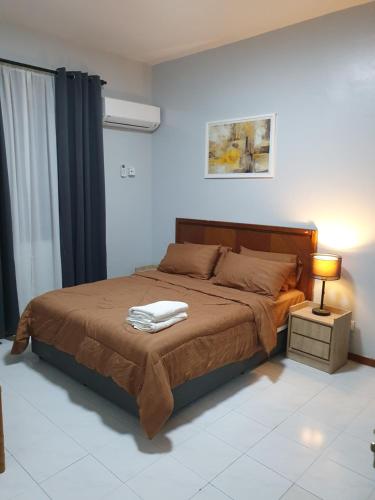 een slaapkamer met een bed en een lamp op een tafel bij Sri Lagenda Apartment Langkawi in Kuah