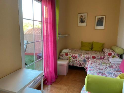 Habitación pequeña con 2 camas y ventana en Familia Anfitriona acoge terraza, en Sevilla