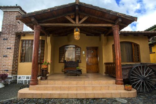 a wooden pergola on the front of a house at Hosteria Rumipamba De Las Rosas in San Miguel de Salcedo
