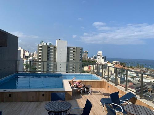 una mujer sentada en una silla junto a una piscina en Studio - frente a praia, en Salvador