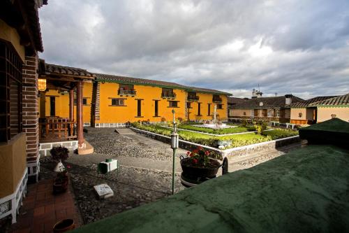 a courtyard with a garden with flowers and buildings at Hosteria Rumipamba De Las Rosas in San Miguel de Salcedo