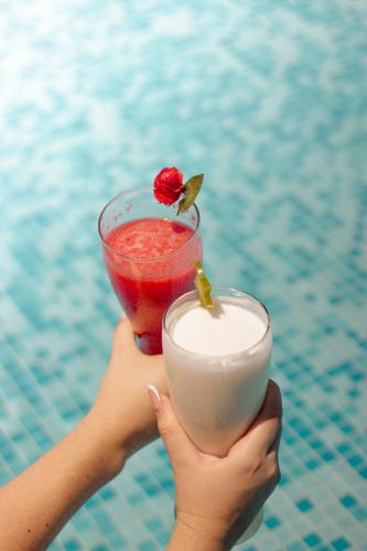 a woman holding a drink in her hands next to a pool at Huku Beach Hostel in Palomino