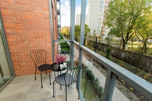 a balcony with two chairs and a table with flowers on it at Scala Rentyear Apartments in Gdańsk