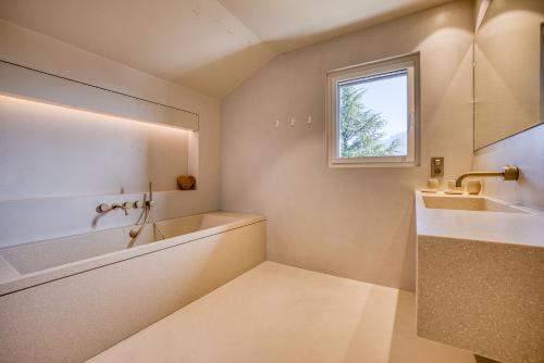 a bathroom with a tub and a sink and a window at Maison Gokan in Sévrier