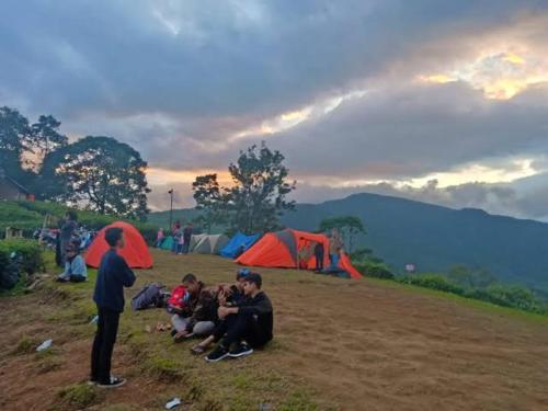 a group of people sitting on a field with tents at view cemping glamping in Bukittinggi