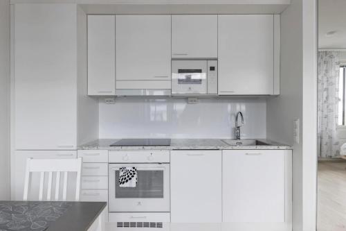 una cocina blanca con armarios blancos y fregadero en Beautiful Modern City Apartment en Kuopio