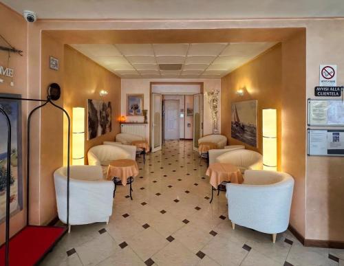 uma sala de espera com cadeiras e mesas brancas em Hotel Avogadro em San Pellegrino Terme