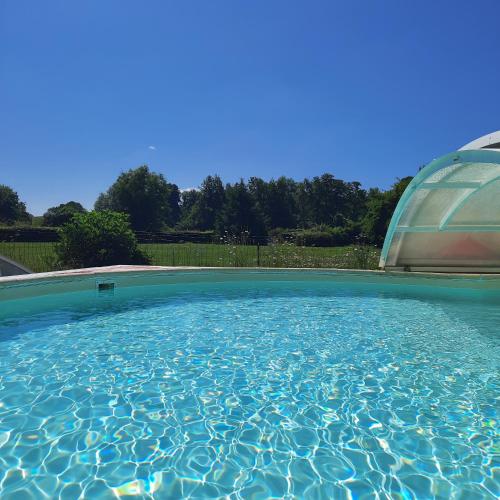 a large swimming pool with a domed structure at Les 2 chaumières avec piscine in Épinay