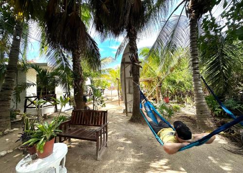 a man laying in a hammock in a resort at Sirenas Caribbean Rooms Holbox in Holbox Island