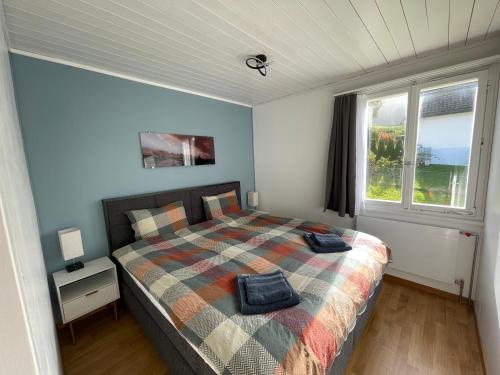 a bedroom with a bed with a checked blanket and a window at Stockberghüsli in Nesslau