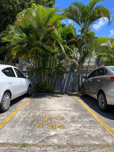two cars parked in a parking lot with palm trees at COBERTURA COMPLETAMENTE MOBILIADA PRÓX AO AEROPORTO DE SALVADOR E PRAIAS CAPACIDADE 14 PESSOAS i in Lauro de Freitas
