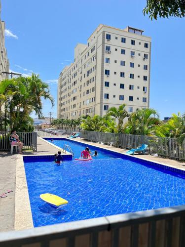 a swimming pool with people playing in the water at Cobertura Climatizada com Suíte à 2km do Aeroporto de Salvador e Praias in Lauro de Freitas
