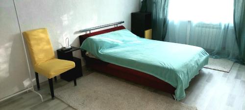 sypialnia z łóżkiem i żółtym krzesłem w obiekcie Квартира по вул Липківського 43 w Kijowie