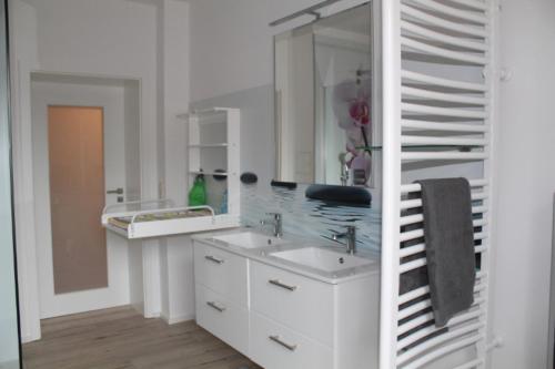 Baño blanco con lavabo y espejo en Ferienwohnung Schöneck en Schöneck