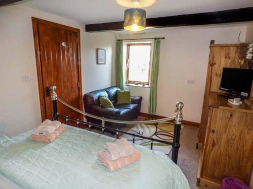 a bedroom with a bed and a couch and a chair at Bank End Barn in Grizebeck