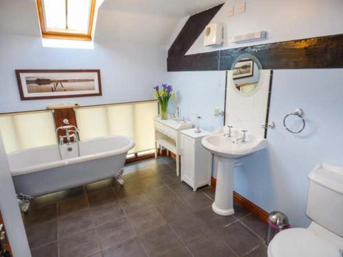 a bathroom with two sinks and a tub and a toilet at Bank End Barn in Grizebeck