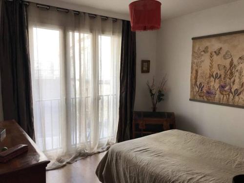 une chambre avec un lit et une grande fenêtre dans l'établissement Bel et grand appartement chaleureux hyper centre, à Avignon