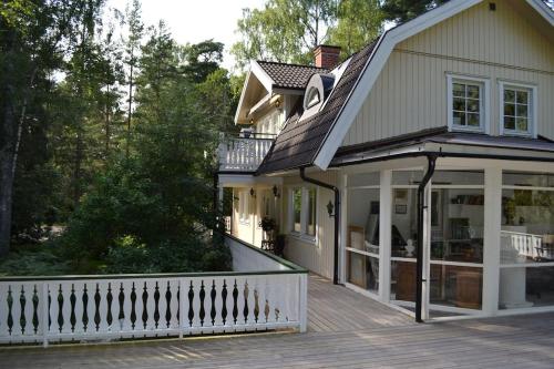 a house with a porch and a white fence at Havsnära Motorbåt 12 Cyklar 18+Beds VedBastu Hav! in Djurhamn