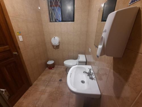 a bathroom with a white sink and a toilet at Hostal David Alejandro in Quito