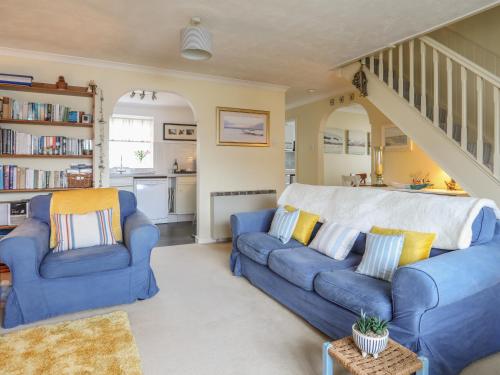 a living room with blue couches and a staircase at Wingelock in Rhosneigr
