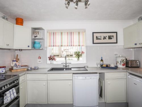 a kitchen with white cabinets and a sink at Wingelock in Rhosneigr