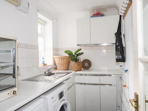 a white kitchen with a sink and a dishwasher at Wingelock in Rhosneigr