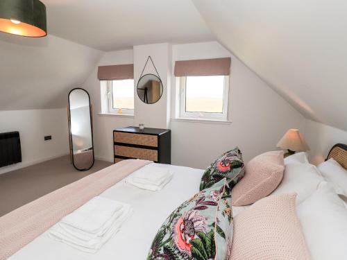 a bedroom with a white bed and a mirror at Park Cottage in Carinish