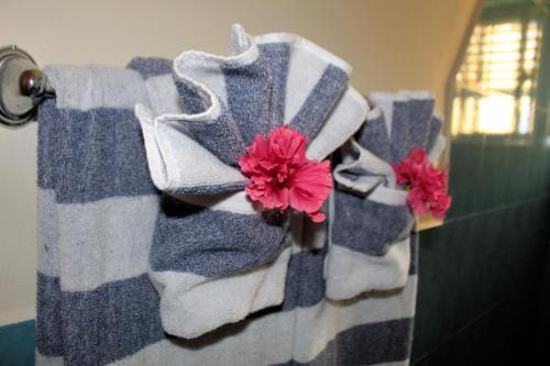 a bunch of towels hanging on a towel rack with flowers at Casa Palma Placencia in Placencia