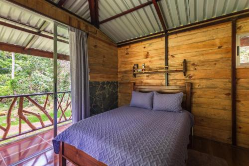 a bedroom in a log cabin with a bed and a window at Hotel Rivel - Restaurant & Nature Retreat in Turrialba