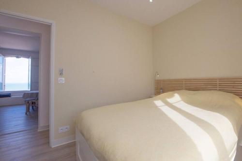 - une chambre blanche avec un lit dans l'établissement La BALEINE BLEUE, à Saint-Aubin-sur-Mer