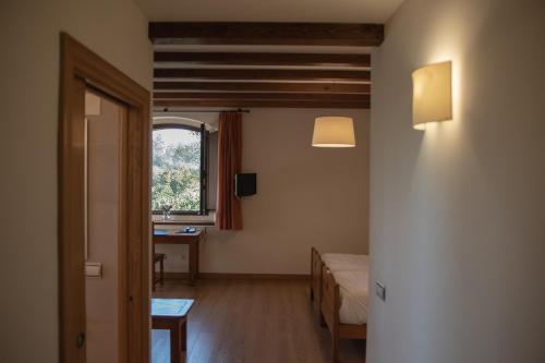 a room with a bed and a table and a window at OLATZEA LANDA HOTELA in Arbizu