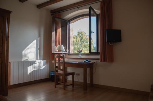 a desk with a chair in a room with a window at OLATZEA LANDA HOTELA in Arbizu