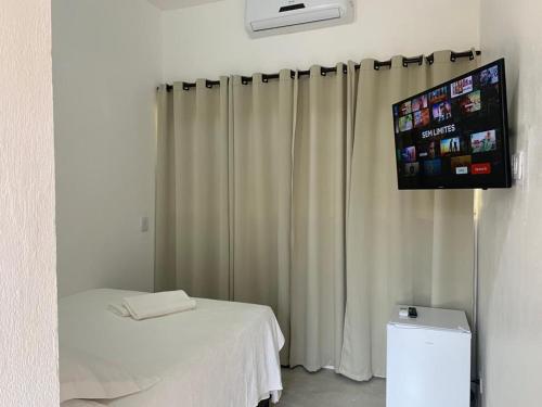 a room with a bed and a flat screen tv at Apartamentos com cachoeira no quintal in Ilhabela