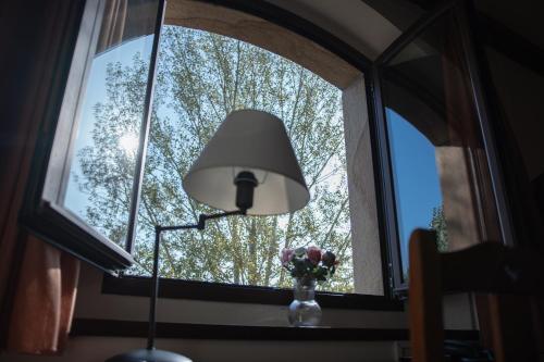 a lamp and a vase of flowers in a window at OLATZEA LANDA HOTELA in Arbizu
