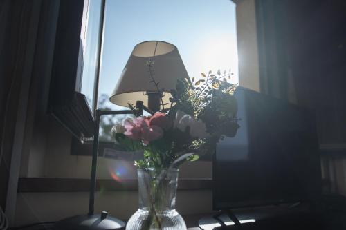 a vase of flowers on a table next to a lamp at OLATZEA LANDA HOTELA in Arbizu