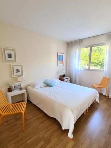 - une chambre avec un grand lit blanc et deux chaises dans l'établissement Appartement Les Oliviers, à Nice