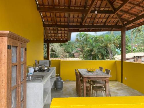 cocina con mesa y pared amarilla en Apartamentos com cachoeira no quintal, en Ilhabela
