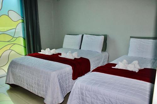 two beds in a room with white towels on them at Marcone Lima - Chalés in Barreirinhas