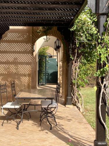 a patio with a table and chairs and an archway at Villa Nooreben, à Marrakech in Marrakech