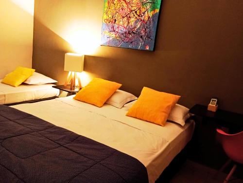 2 bedden in een hotelkamer met gele kussens bij Nomad - Norte Sul, Cambui in Campinas