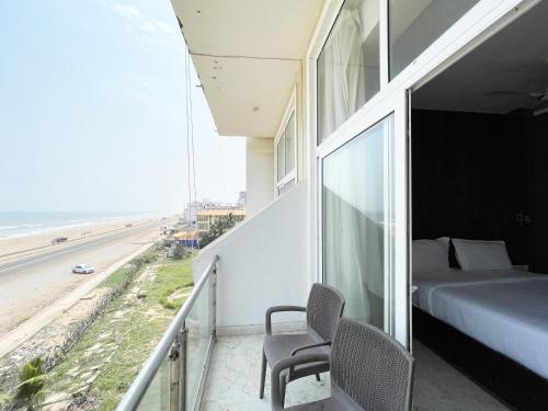 un balcón con una cama y sillas y la playa en Hotel TBS ! PURI all-rooms-sea-view fully-air-conditioned-hotel with-lift-and-parking-facility breakfast-included, en Puri