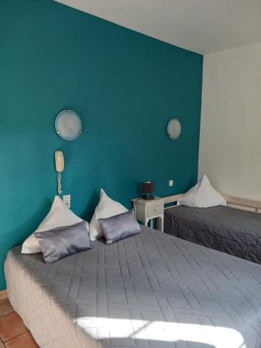 a bedroom with two beds and a blue wall at Hotel Du Lac in Château-Arnoux-Saint-Auban