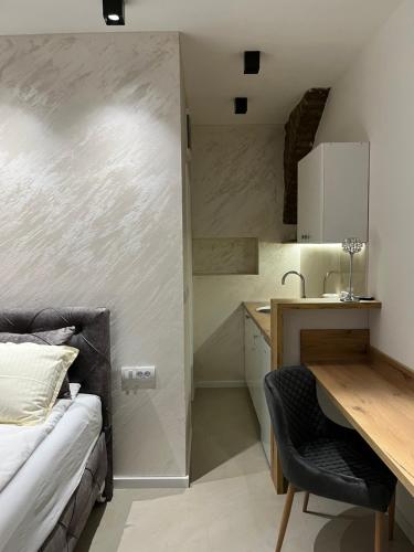 a bedroom with a bed and a desk and a kitchen at Dream House in Novi Sad
