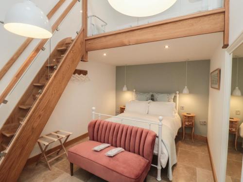 a bedroom with a bed and a staircase and a red chair at Owl Barn in Whitby