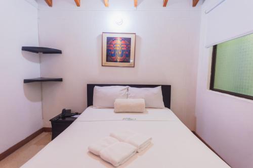 a bedroom with a bed with two white towels on it at Hotel Guatatur in Guatapé