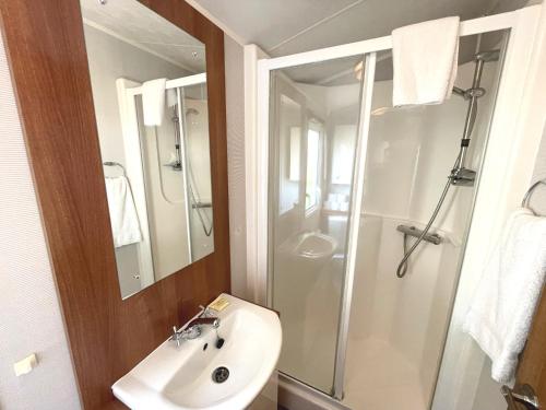 La salle de bains est pourvue d'un lavabo blanc et d'une douche. dans l'établissement Pass the Keys Charming and Cosy Holiday Home in Beautiful Park, à Beattock