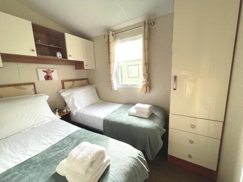 a small bedroom with two beds and a window at Pass the Keys Charming and Cosy Holiday Home in Beautiful Park in Beattock